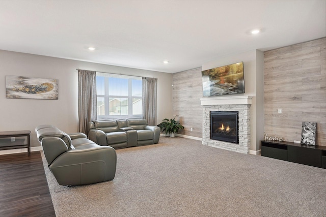 living room with wooden walls and a stone fireplace