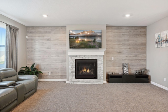 carpeted living room with wood walls and a fireplace