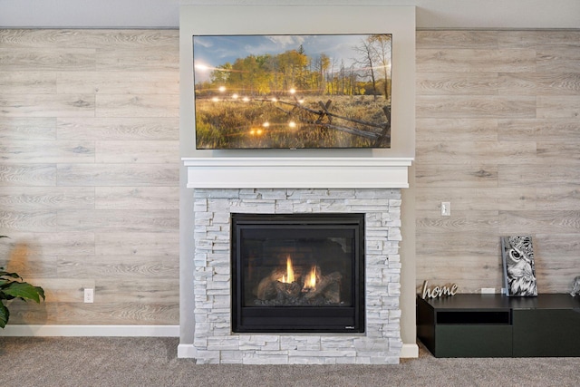 details with wood walls, carpet flooring, and a stone fireplace