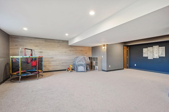 recreation room with carpet flooring and wood walls