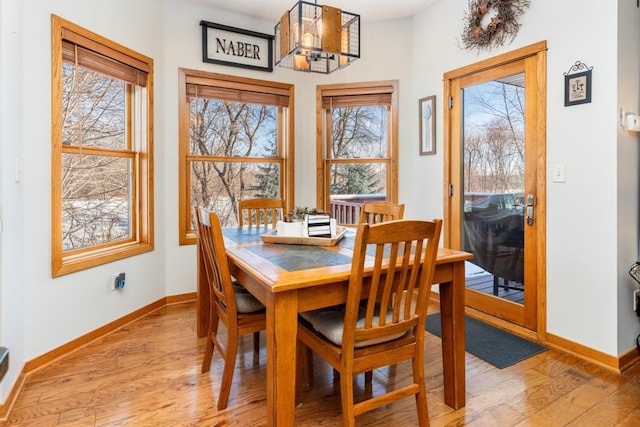 dining room featuring light wood-type flooring, baseboards, and a notable chandelier