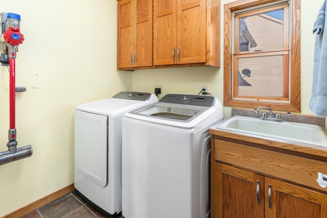 clothes washing area featuring separate washer and dryer, a sink, cabinet space, and baseboards