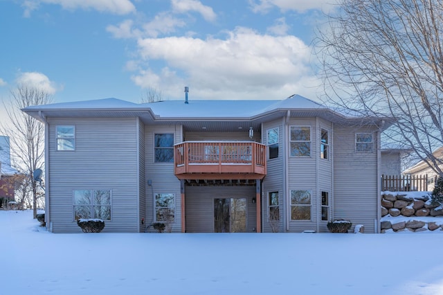 snow covered back of property featuring a wooden deck