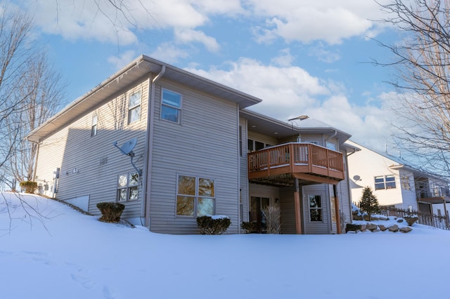 snow covered back of property with a wooden deck