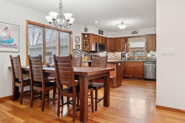 dining room with light wood finished floors, recessed lighting, an inviting chandelier, a textured ceiling, and baseboards