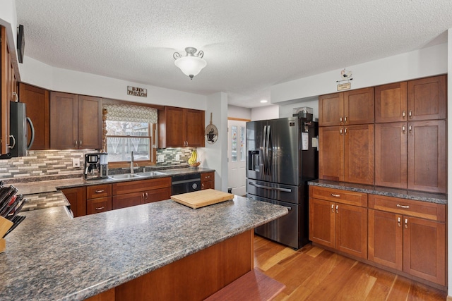 kitchen with light wood finished floors, a sink, stainless steel fridge, dishwasher, and a peninsula