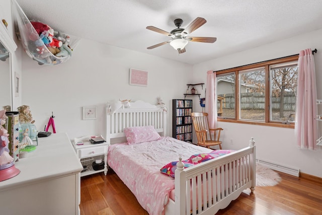 bedroom with a textured ceiling, ceiling fan, a baseboard radiator, and wood finished floors