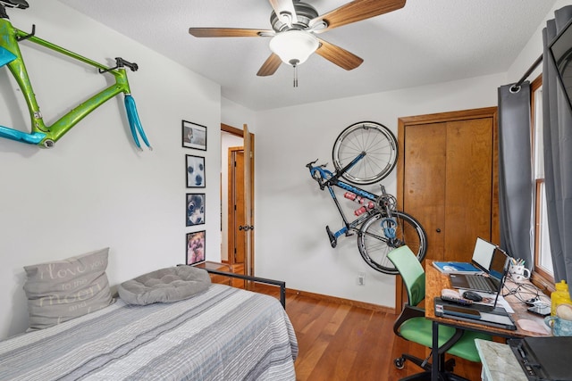 bedroom with a textured ceiling, ceiling fan, wood finished floors, and baseboards