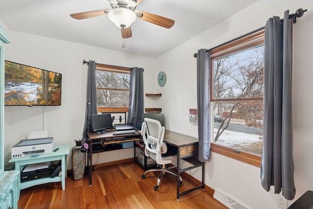 office space featuring ceiling fan, a textured ceiling, wood finished floors, visible vents, and baseboards