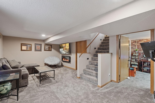 living area featuring baseboards, a glass covered fireplace, carpet, stairs, and a textured ceiling