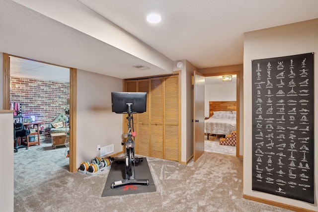 exercise room featuring visible vents, carpet flooring, and a textured ceiling