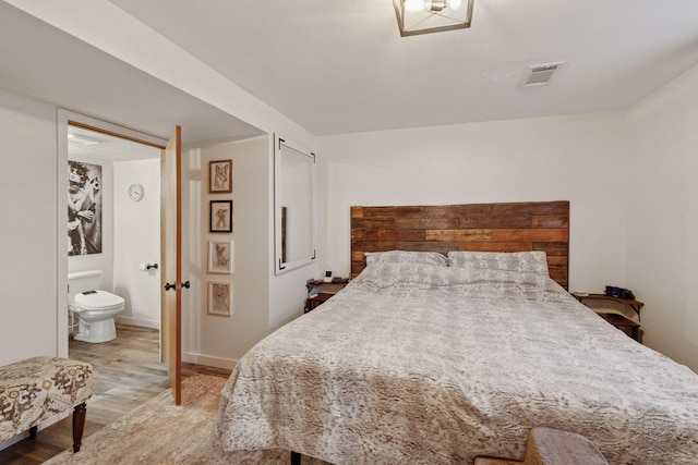 bedroom with light wood-style floors, visible vents, connected bathroom, and baseboards