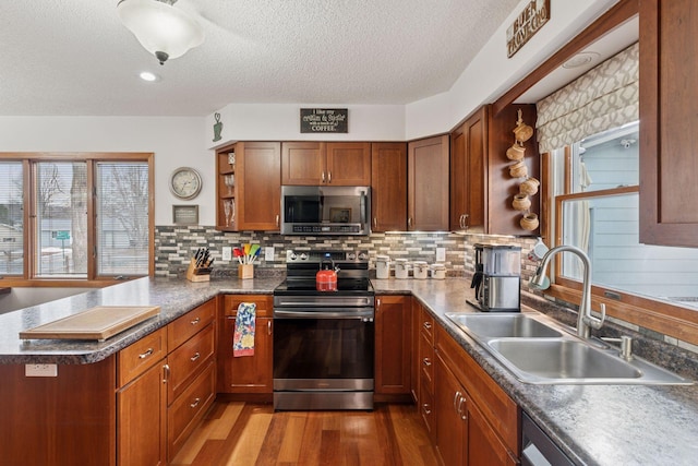 kitchen with a peninsula, stainless steel appliances, light wood-style floors, open shelves, and a sink