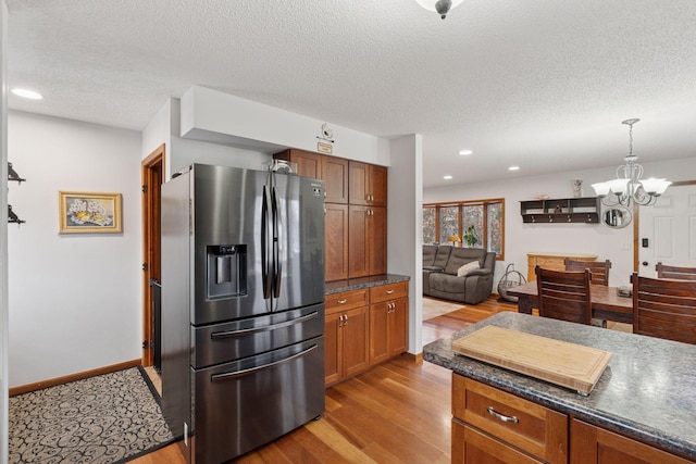 kitchen featuring dark countertops, wood finished floors, decorative light fixtures, stainless steel refrigerator with ice dispenser, and a notable chandelier