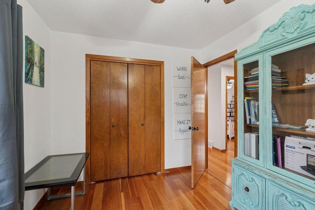 interior space featuring light wood-style flooring, a ceiling fan, and a textured ceiling