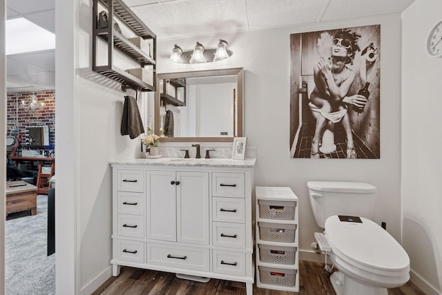 bathroom featuring baseboards, vanity, toilet, and wood finished floors