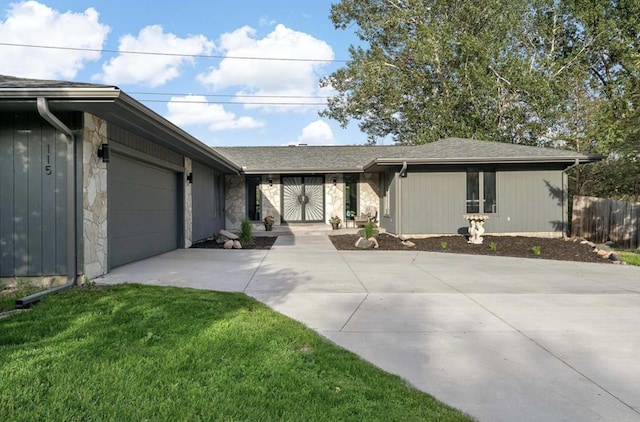 ranch-style house with a front lawn, fence, concrete driveway, a garage, and stone siding