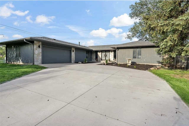 ranch-style home with stone siding, a front lawn, concrete driveway, and an attached garage