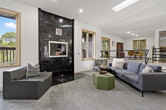 living room with recessed lighting, baseboards, lofted ceiling with skylight, and a fireplace