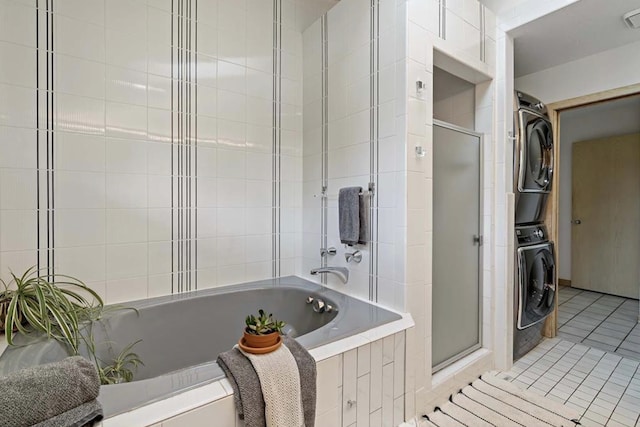 full bathroom featuring tile patterned floors, stacked washer and clothes dryer, a stall shower, and a relaxing tiled tub