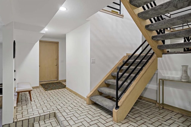 interior space featuring brick floor, stairway, baseboards, and recessed lighting