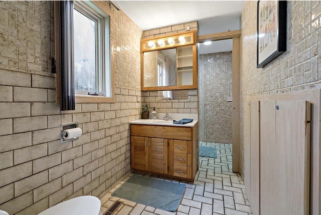 bathroom featuring brick floor, toilet, and vanity