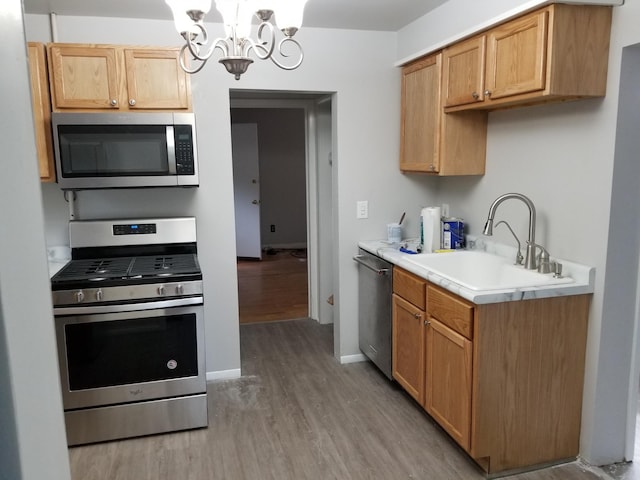 kitchen featuring light hardwood / wood-style floors, sink, appliances with stainless steel finishes, a chandelier, and pendant lighting