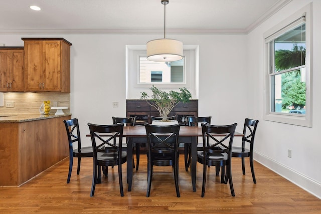 dining area with baseboards, ornamental molding, and wood finished floors