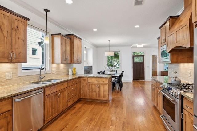 kitchen with a peninsula, a sink, visible vents, appliances with stainless steel finishes, and light stone countertops