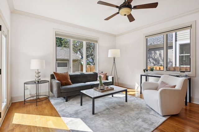 living room with a ceiling fan, crown molding, baseboards, and wood finished floors