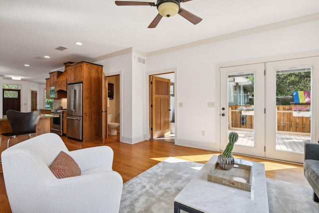 living room featuring ornamental molding, visible vents, baseboards, and wood finished floors