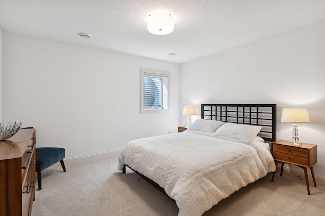 bedroom with light carpet, baseboards, and a textured ceiling