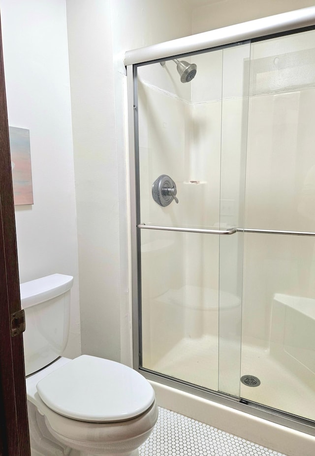 full bath featuring a shower stall, toilet, and tile patterned floors