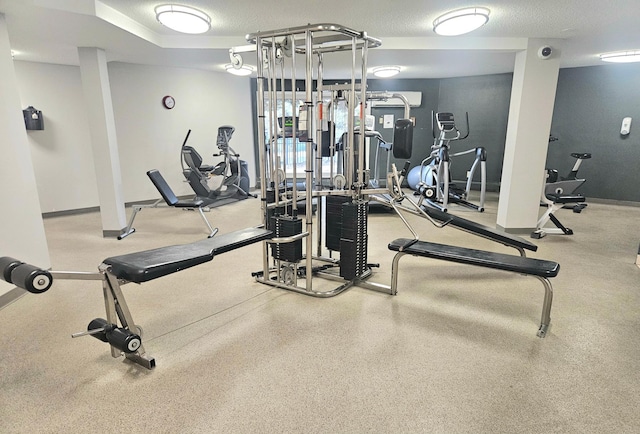 workout area featuring a textured ceiling and baseboards