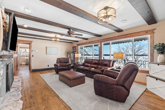 living room featuring light wood-type flooring, a healthy amount of sunlight, beamed ceiling, and a fireplace