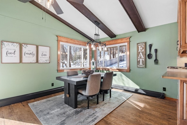 dining room featuring lofted ceiling with beams, wood finished floors, baseboards, and ceiling fan