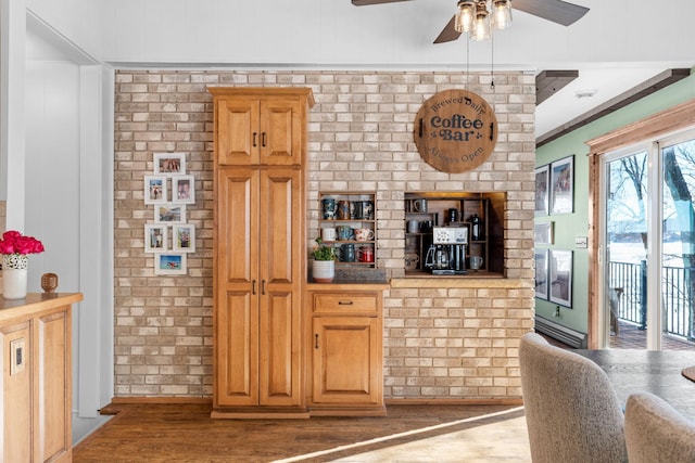 kitchen with ceiling fan, brick wall, wood finished floors, and crown molding