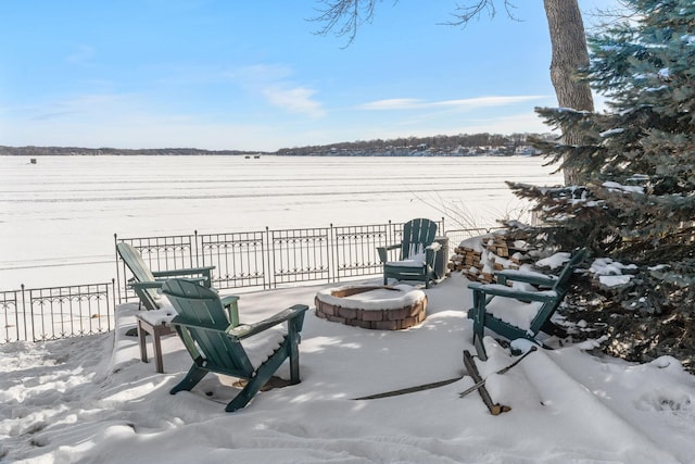 view of patio / terrace featuring a water view, fence, and an outdoor fire pit