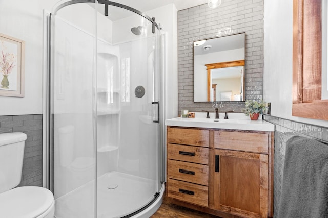 bathroom featuring a shower stall, tile walls, and toilet