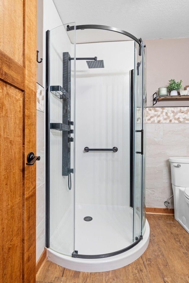 bathroom featuring a stall shower, tile walls, and wood finished floors