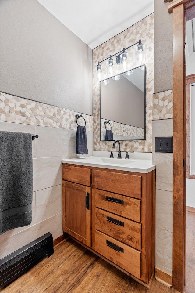 bathroom with a wainscoted wall, tile walls, wood finished floors, and vanity