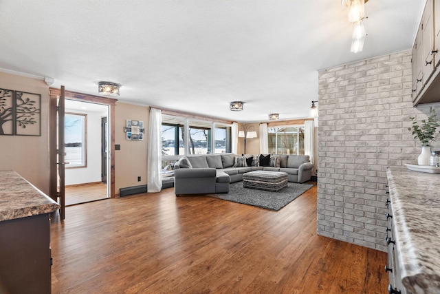 living room featuring wood finished floors, baseboards, brick wall, a textured ceiling, and crown molding