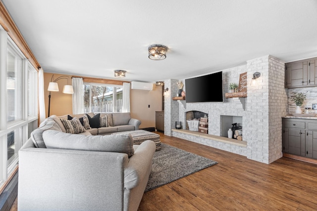 living room featuring a fireplace, a wall mounted AC, and wood finished floors