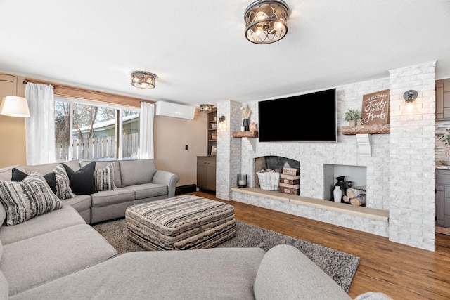 living room featuring a fireplace, an AC wall unit, and wood finished floors