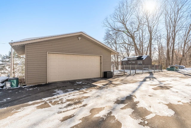 detached garage featuring cooling unit and fence