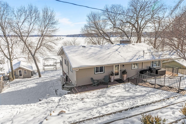 snow covered house with a deck and fence