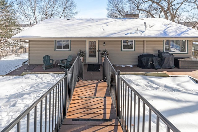 snow covered property featuring a chimney and a deck