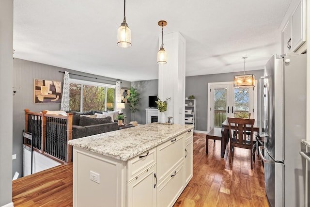kitchen with white cabinets, freestanding refrigerator, open floor plan, decorative light fixtures, and light wood-type flooring
