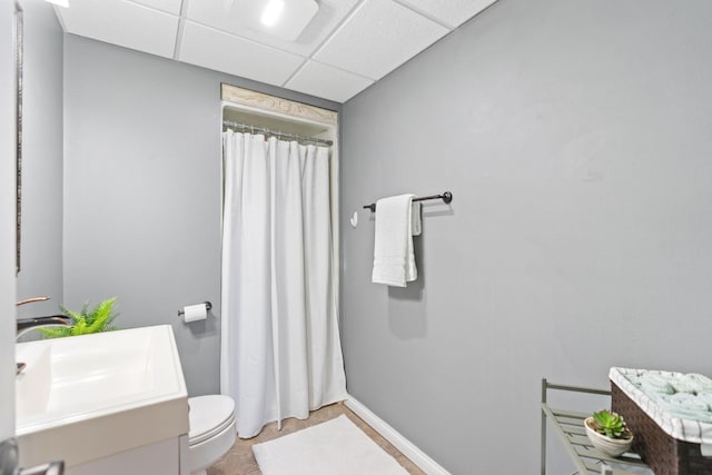 bathroom featuring vanity, toilet, a paneled ceiling, baseboards, and a shower with curtain