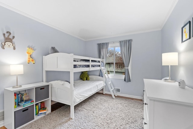bedroom with crown molding, baseboards, wood finished floors, and visible vents